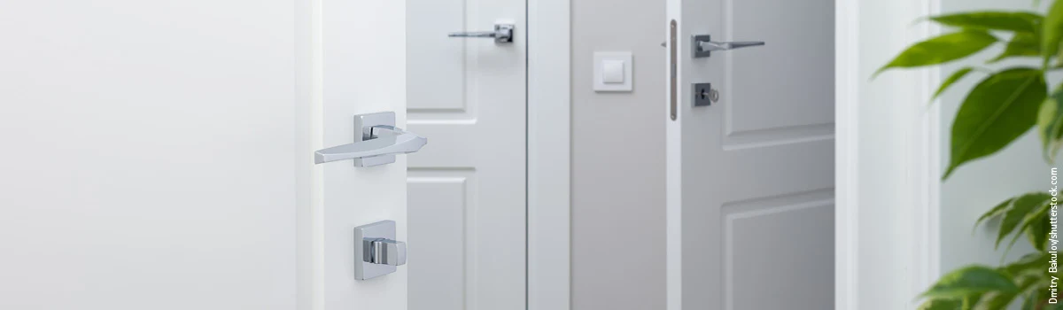 Drei weiße Türen mit Kassetten und silberfarbenen Türdrückern sowie unterschiedlichen Schlössern